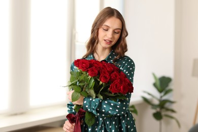 Photo of Beautiful woman with bouquet of roses at home