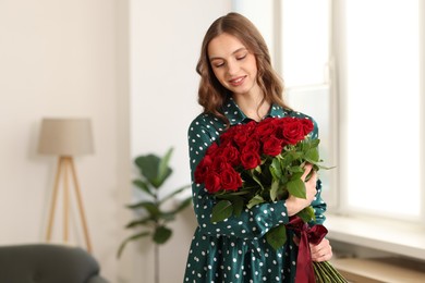 Photo of Smiling woman with bouquet of roses at home. Space for text