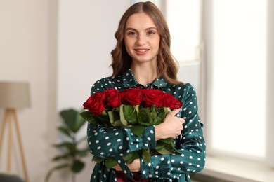 Photo of Smiling woman with bouquet of roses at home