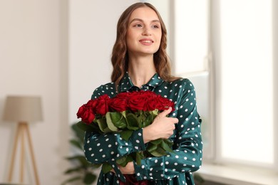 Photo of Smiling woman with bouquet of roses at home