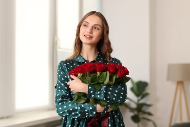 Photo of Smiling woman with bouquet of roses at home