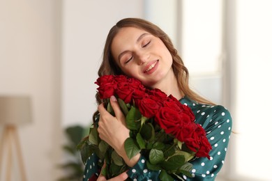 Photo of Smiling woman with bouquet of roses at home