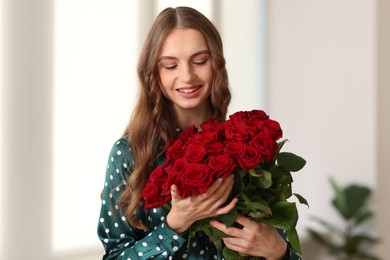 Photo of Smiling woman with bouquet of roses at home