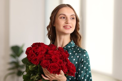 Photo of Smiling woman with bouquet of roses at home