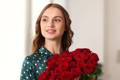 Photo of Smiling woman with bouquet of roses at home