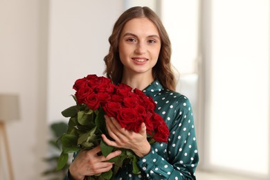 Photo of Smiling woman with bouquet of roses at home