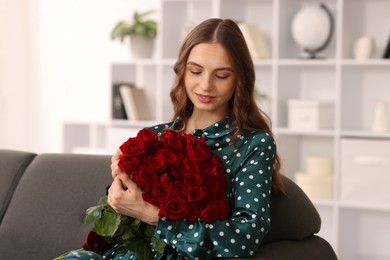 Photo of Beautiful woman with bouquet of roses on sofa at home