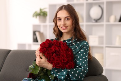 Photo of Smiling woman with bouquet of roses on sofa at home