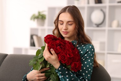 Photo of Beautiful woman with bouquet of roses on sofa at home