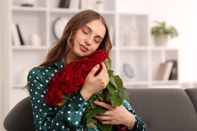 Photo of Beautiful woman with bouquet of roses on sofa at home