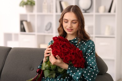 Photo of Smiling woman with bouquet of roses on sofa at home