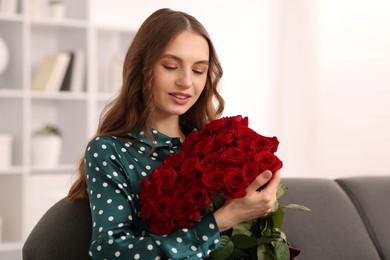 Photo of Smiling woman with bouquet of roses on sofa at home