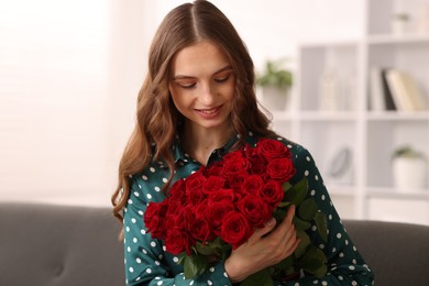 Photo of Smiling woman with bouquet of roses on sofa at home