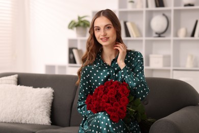 Photo of Smiling woman with bouquet of roses on sofa at home