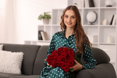 Photo of Smiling woman with bouquet of roses on sofa at home. Space for text