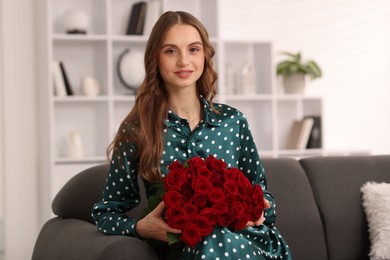 Photo of Smiling woman with bouquet of roses on sofa at home