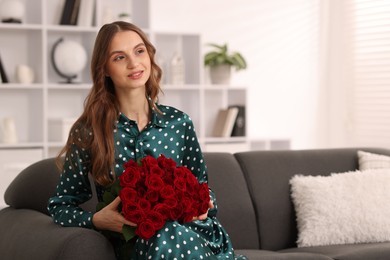 Photo of Smiling woman with bouquet of roses on sofa at home. Space for text