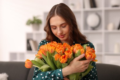 Photo of Beautiful woman with bouquet of tulips at home