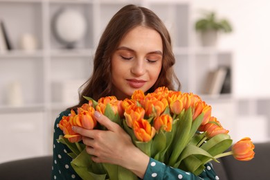 Photo of Beautiful woman with bouquet of tulips at home