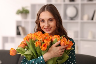 Photo of Smiling woman with bouquet of tulips at home