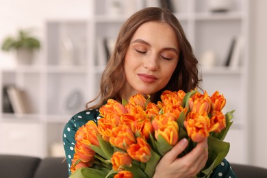 Photo of Beautiful woman with bouquet of tulips at home