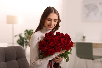 Photo of Smiling woman with bouquet of roses at home