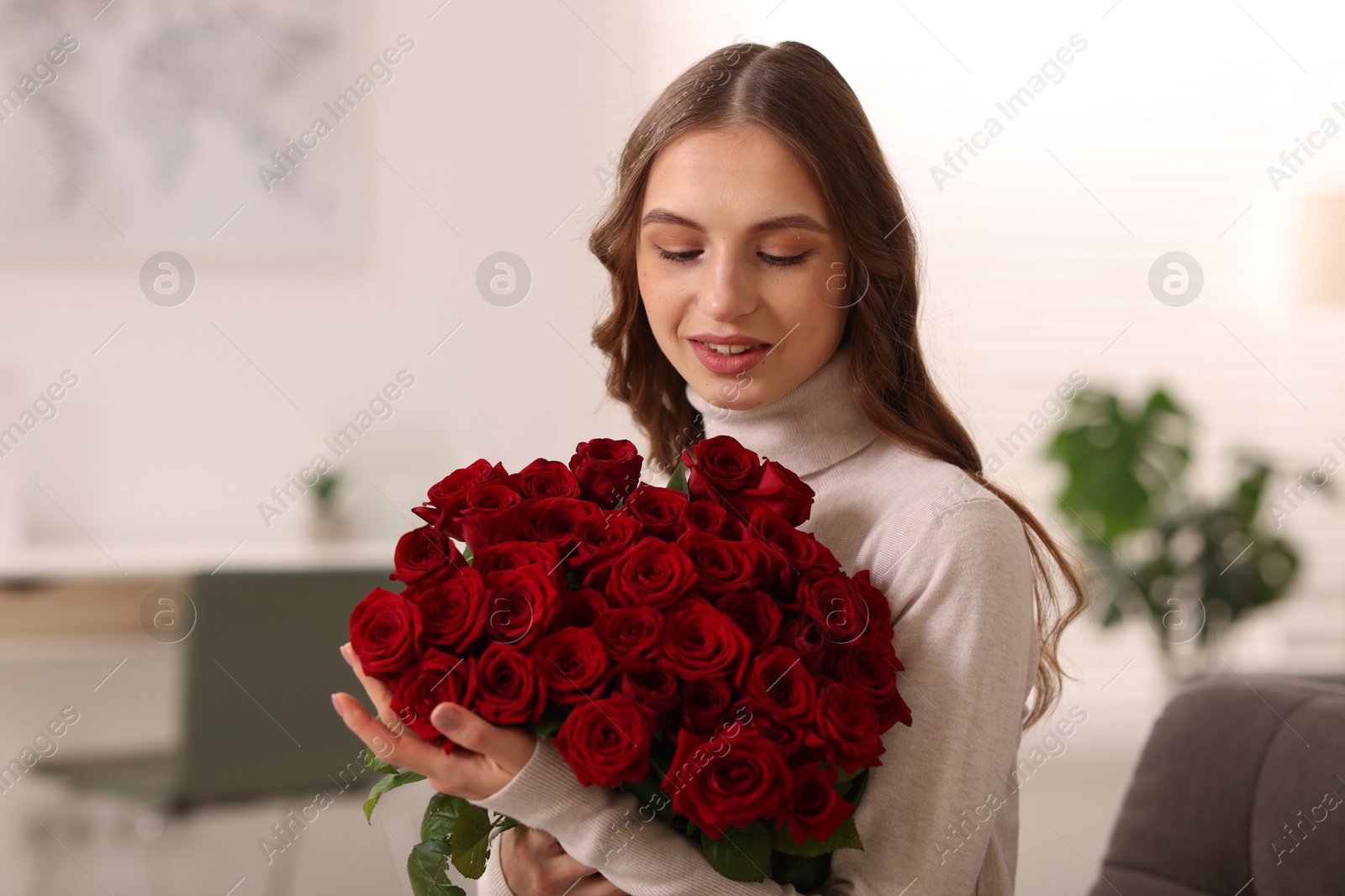 Photo of Smiling woman with bouquet of roses at home