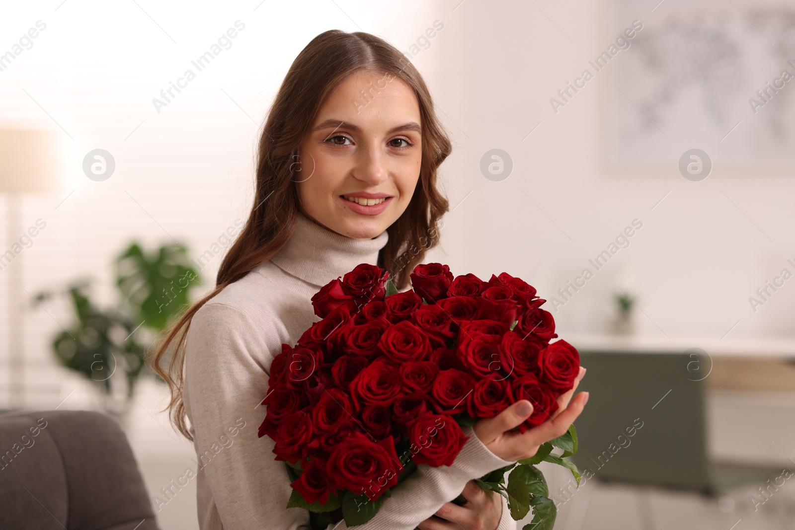 Photo of Smiling woman with bouquet of roses at home