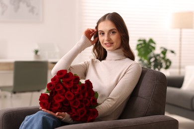 Photo of Smiling woman with bouquet of roses on armchair at home