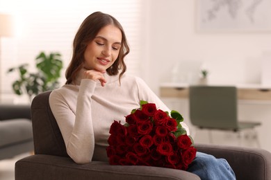 Photo of Smiling woman with bouquet of roses on armchair at home