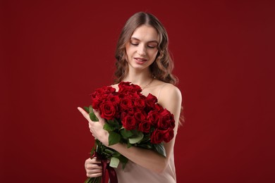 Photo of Smiling woman with bouquet of roses on dark red background