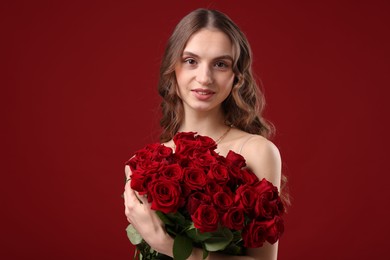 Photo of Smiling woman with bouquet of roses on dark red background