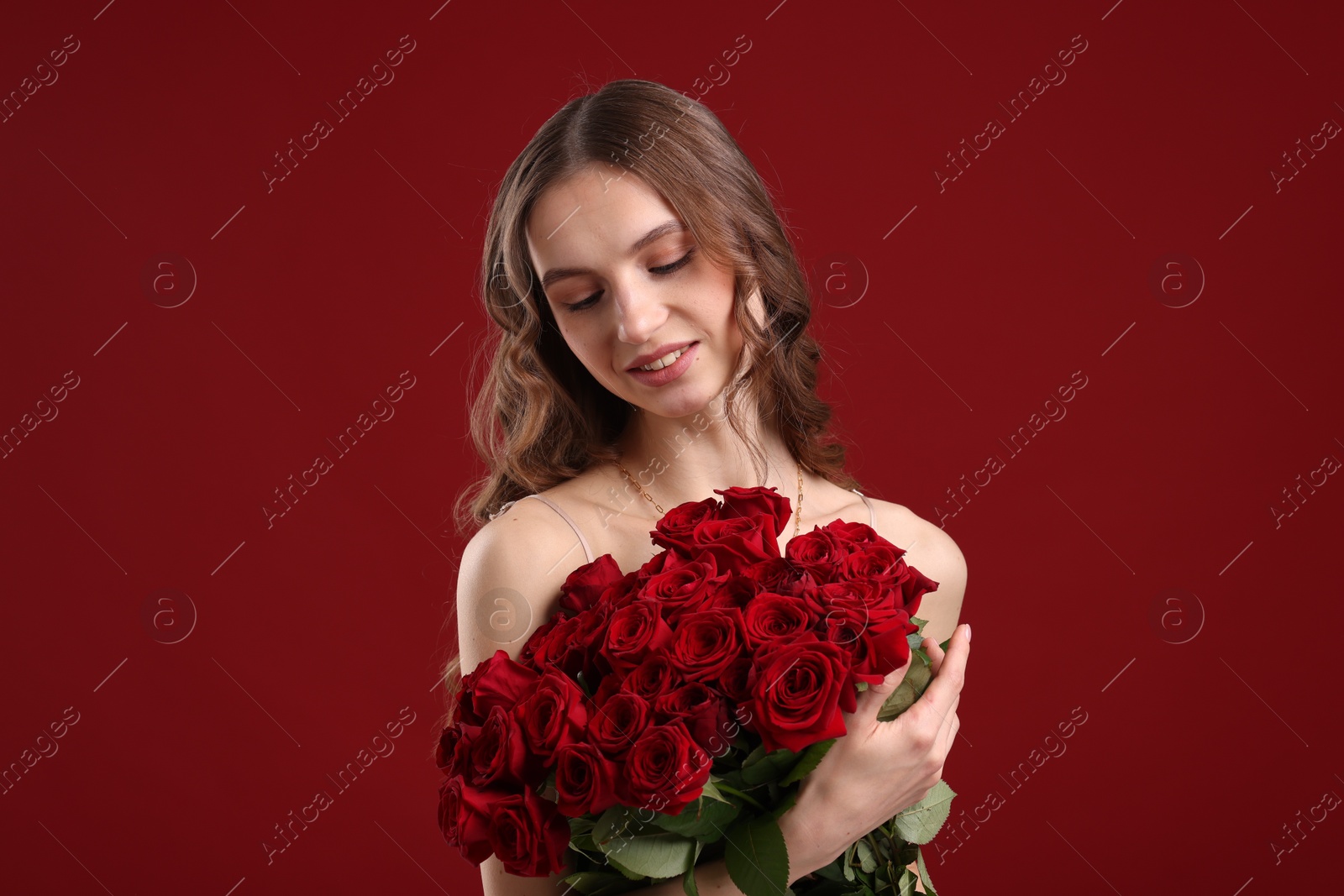 Photo of Smiling woman with bouquet of roses on dark red background