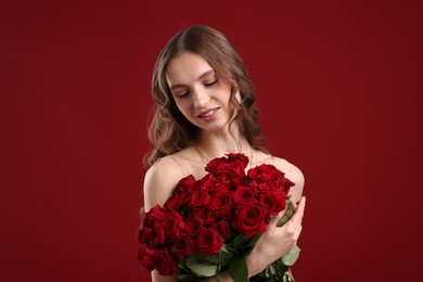 Photo of Smiling woman with bouquet of roses on dark red background