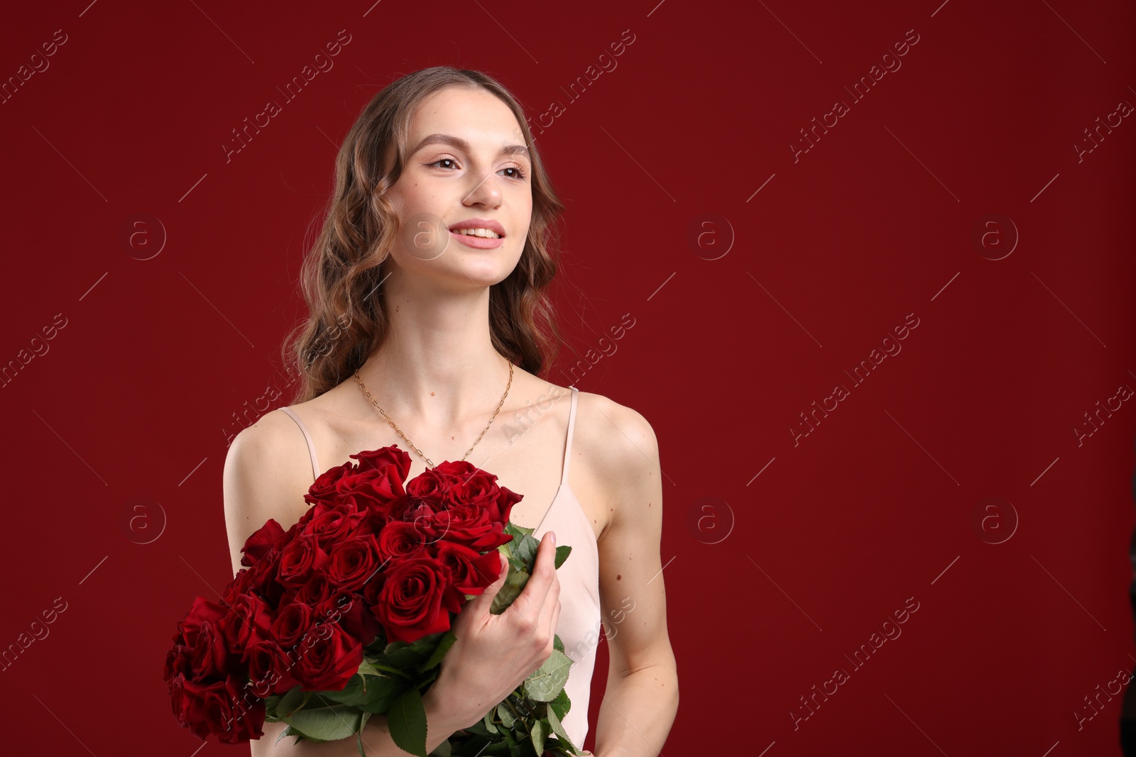 Photo of Smiling woman with bouquet of roses on dark red background. Space for text