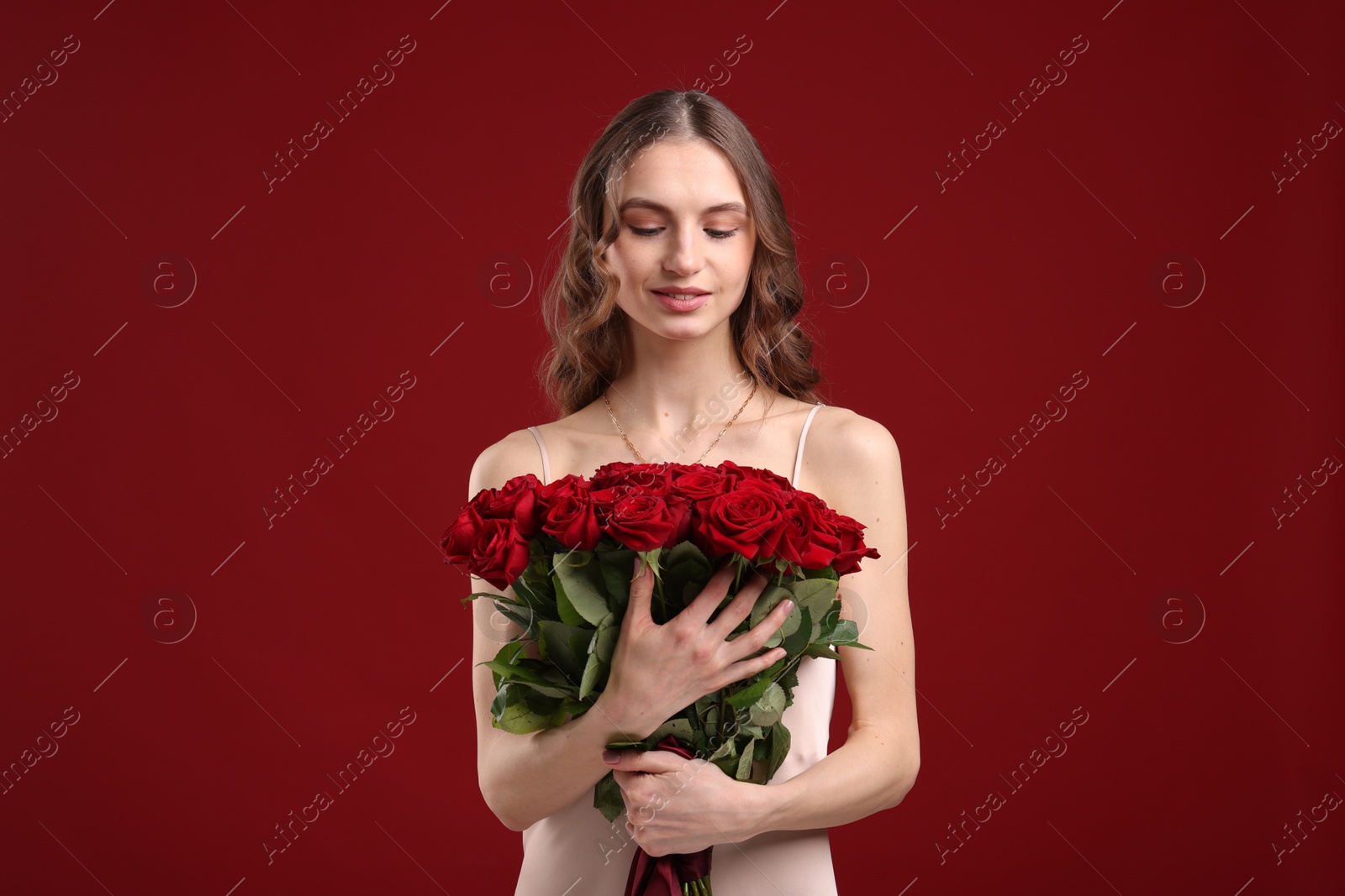 Photo of Smiling woman with bouquet of roses on dark red background