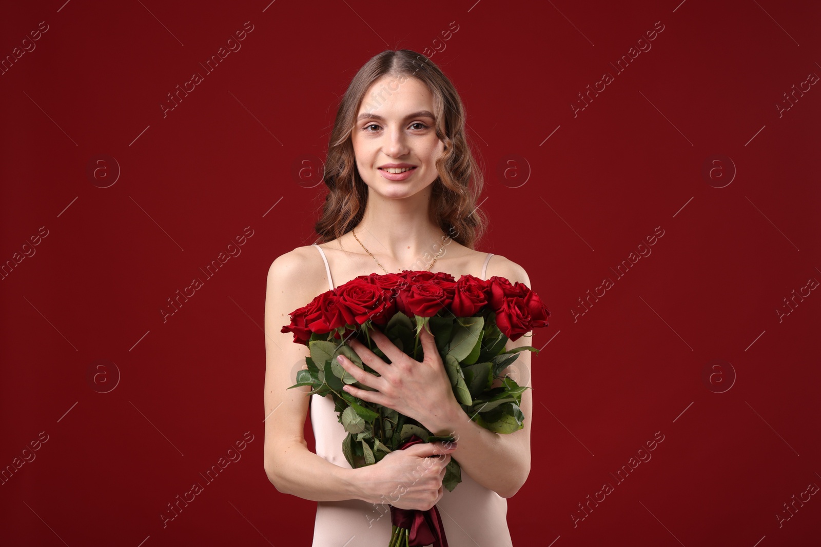 Photo of Smiling woman with bouquet of roses on dark red background