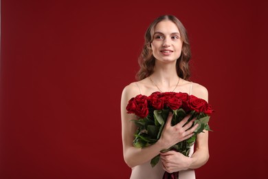 Photo of Smiling woman with bouquet of roses on dark red background. Space for text