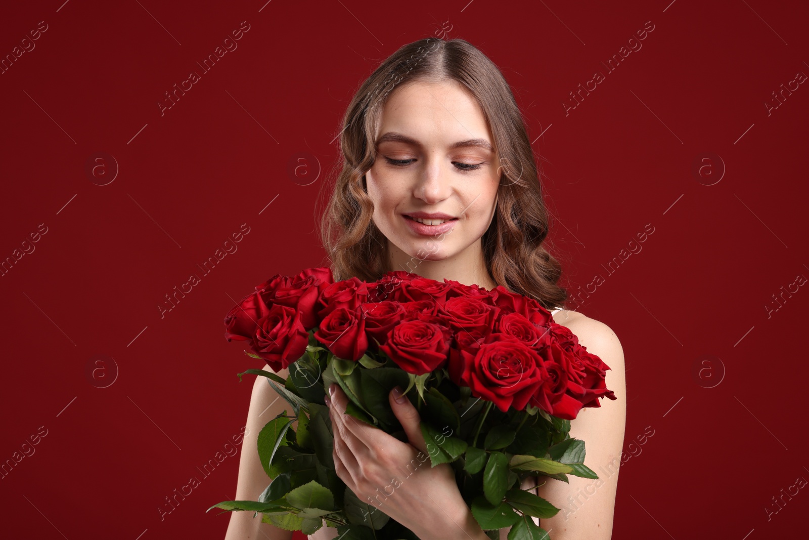 Photo of Smiling woman with bouquet of roses on dark red background