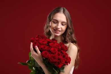 Photo of Smiling woman with bouquet of roses on dark red background