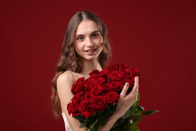 Photo of Smiling woman with bouquet of roses on dark red background