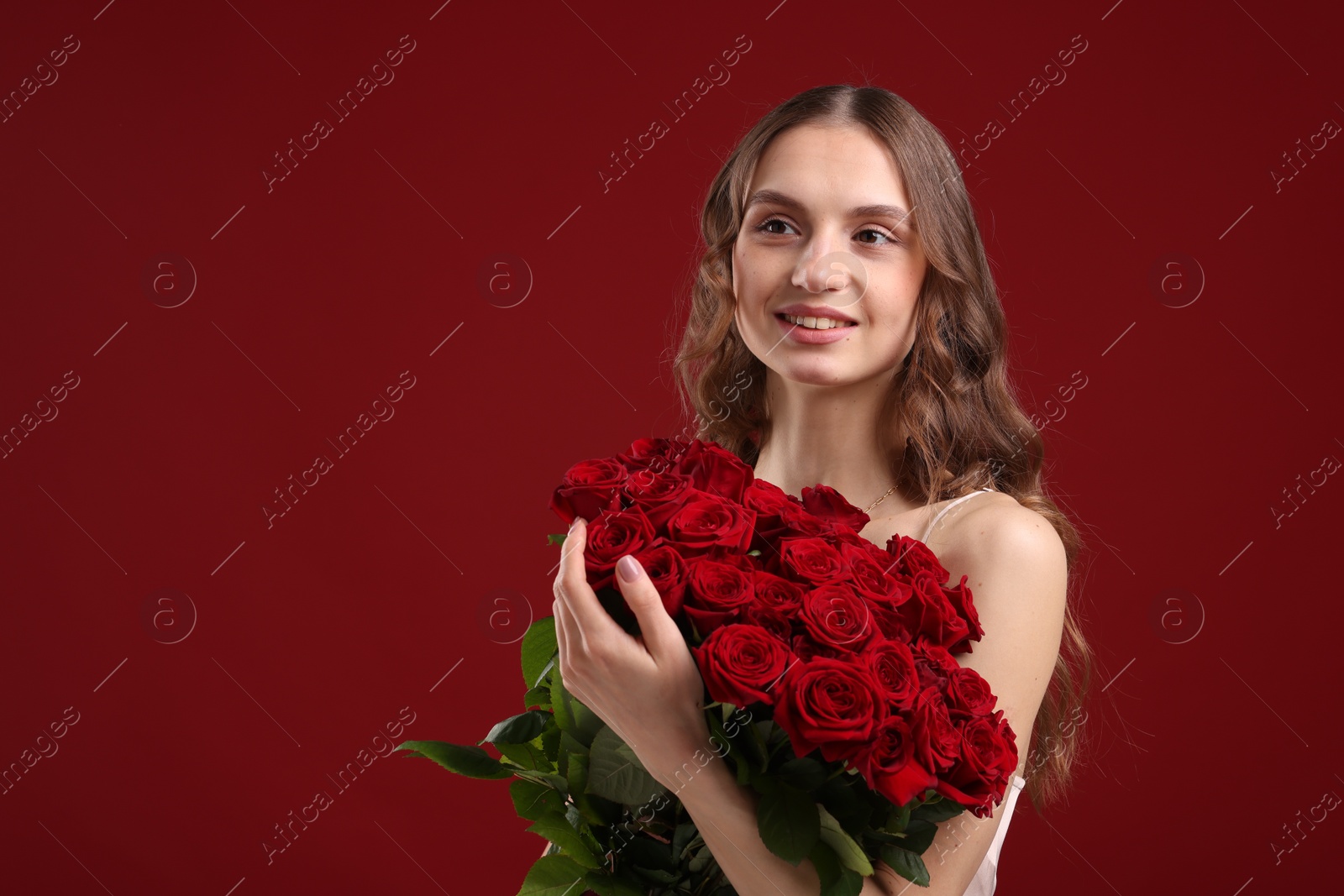 Photo of Smiling woman with bouquet of roses on dark red background. Space for text