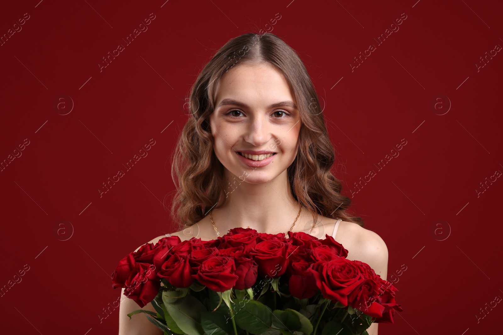 Photo of Smiling woman with bouquet of roses on dark red background