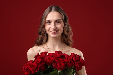 Photo of Smiling woman with bouquet of roses on dark red background