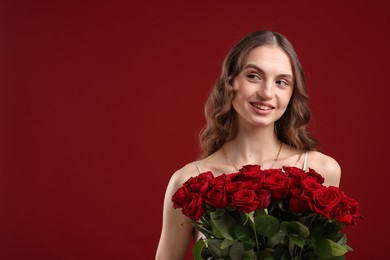 Photo of Smiling woman with bouquet of roses on dark red background. Space for text