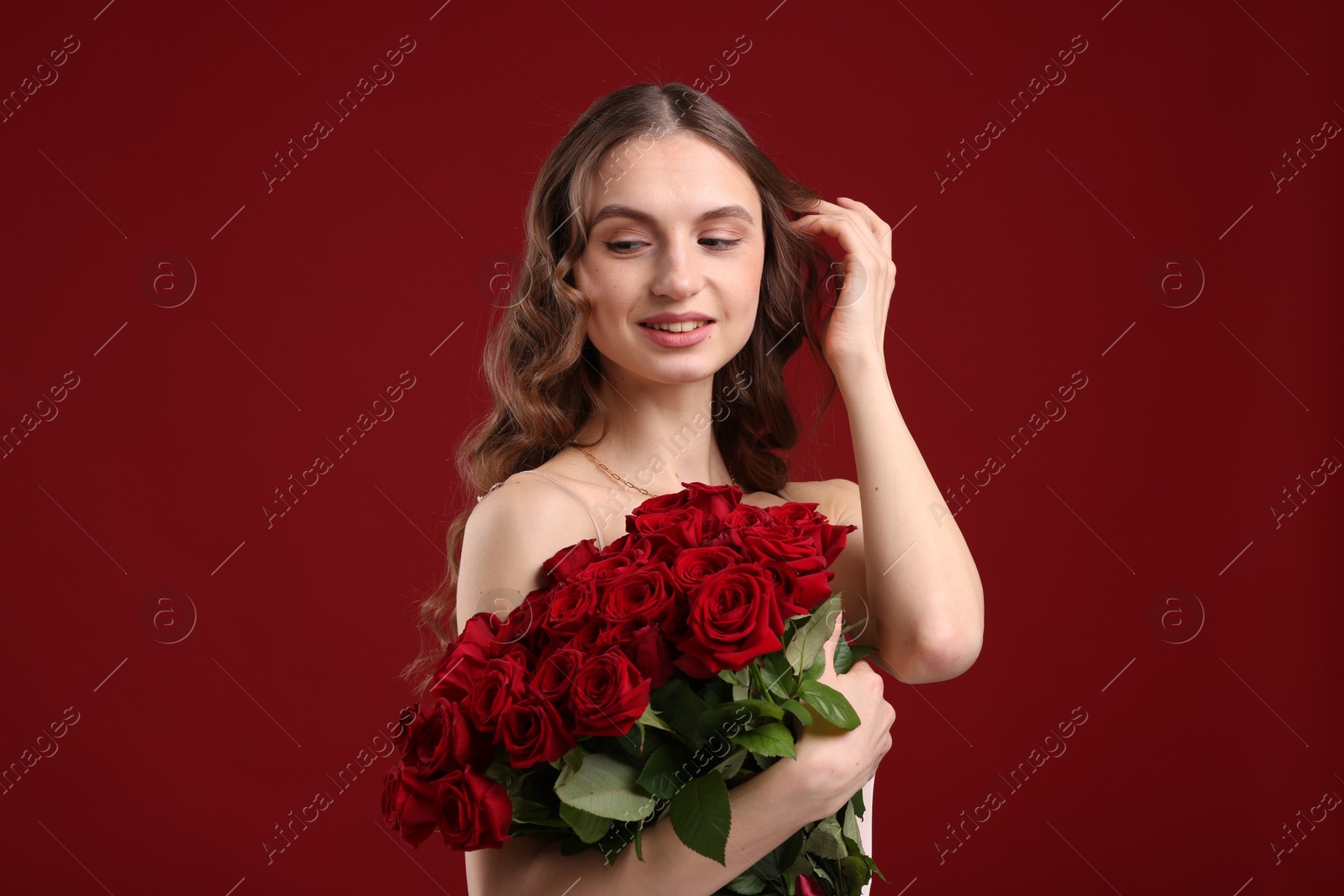 Photo of Smiling woman with bouquet of roses on dark red background