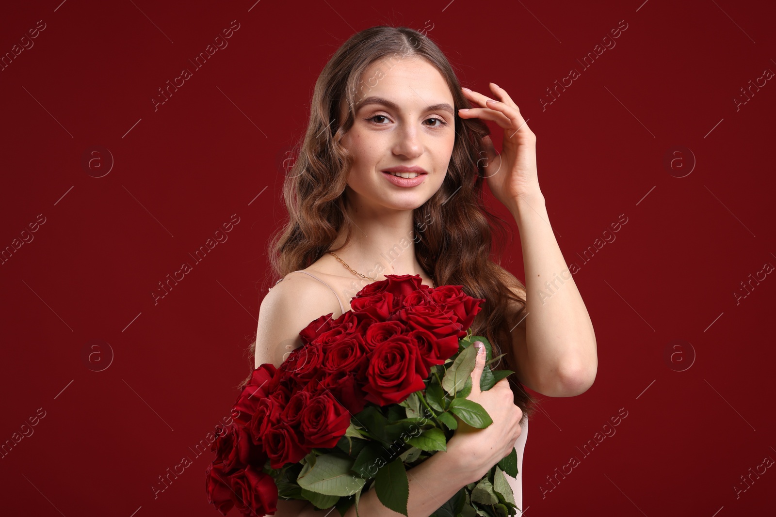 Photo of Smiling woman with bouquet of roses on dark red background