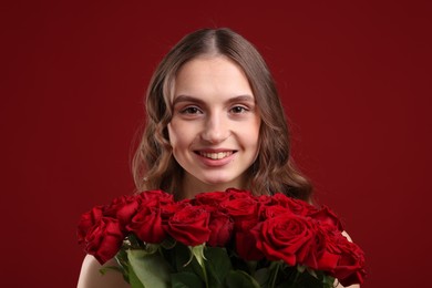 Photo of Smiling woman with bouquet of roses on dark red background