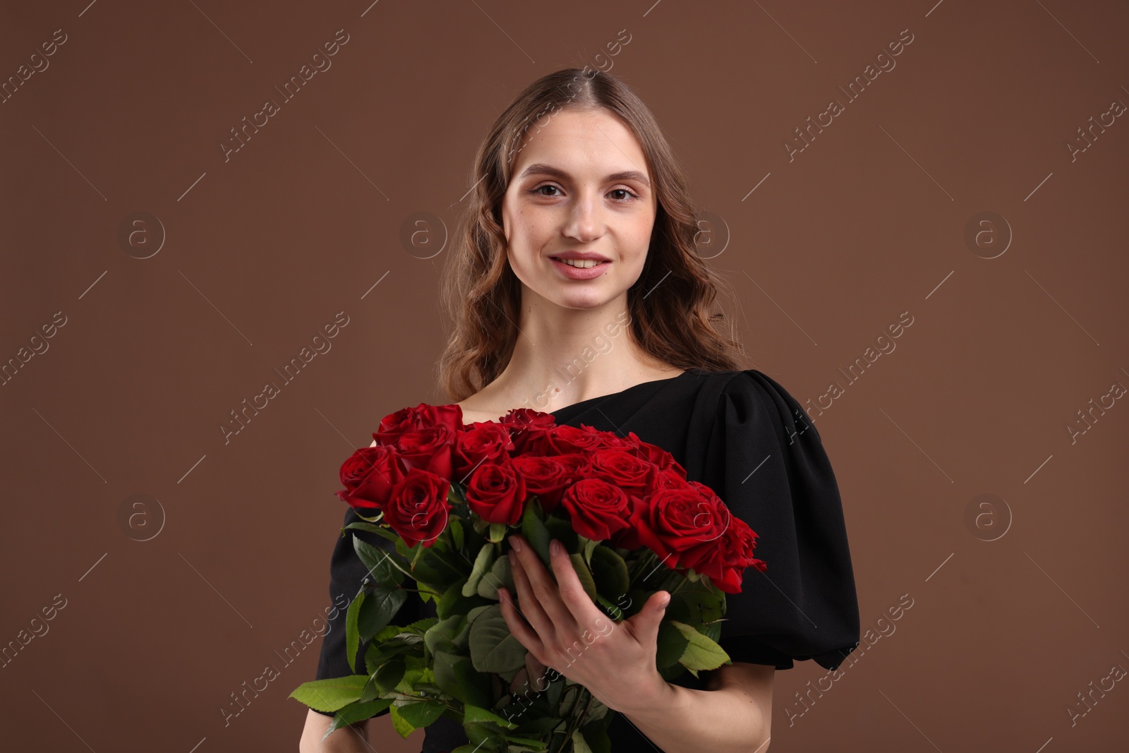 Photo of Smiling woman with bouquet of roses on brown background