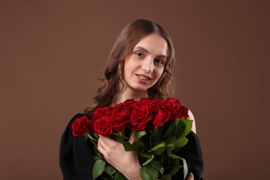 Photo of Smiling woman with bouquet of roses on brown background